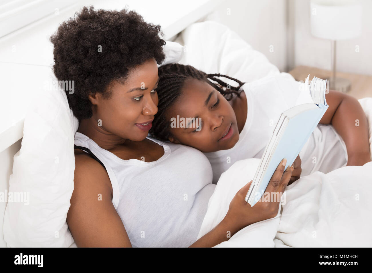 Mutter Lesung eine Gutenachtgeschichte Buchen Sie zu Ihrer Tochter im Bett Stockfoto