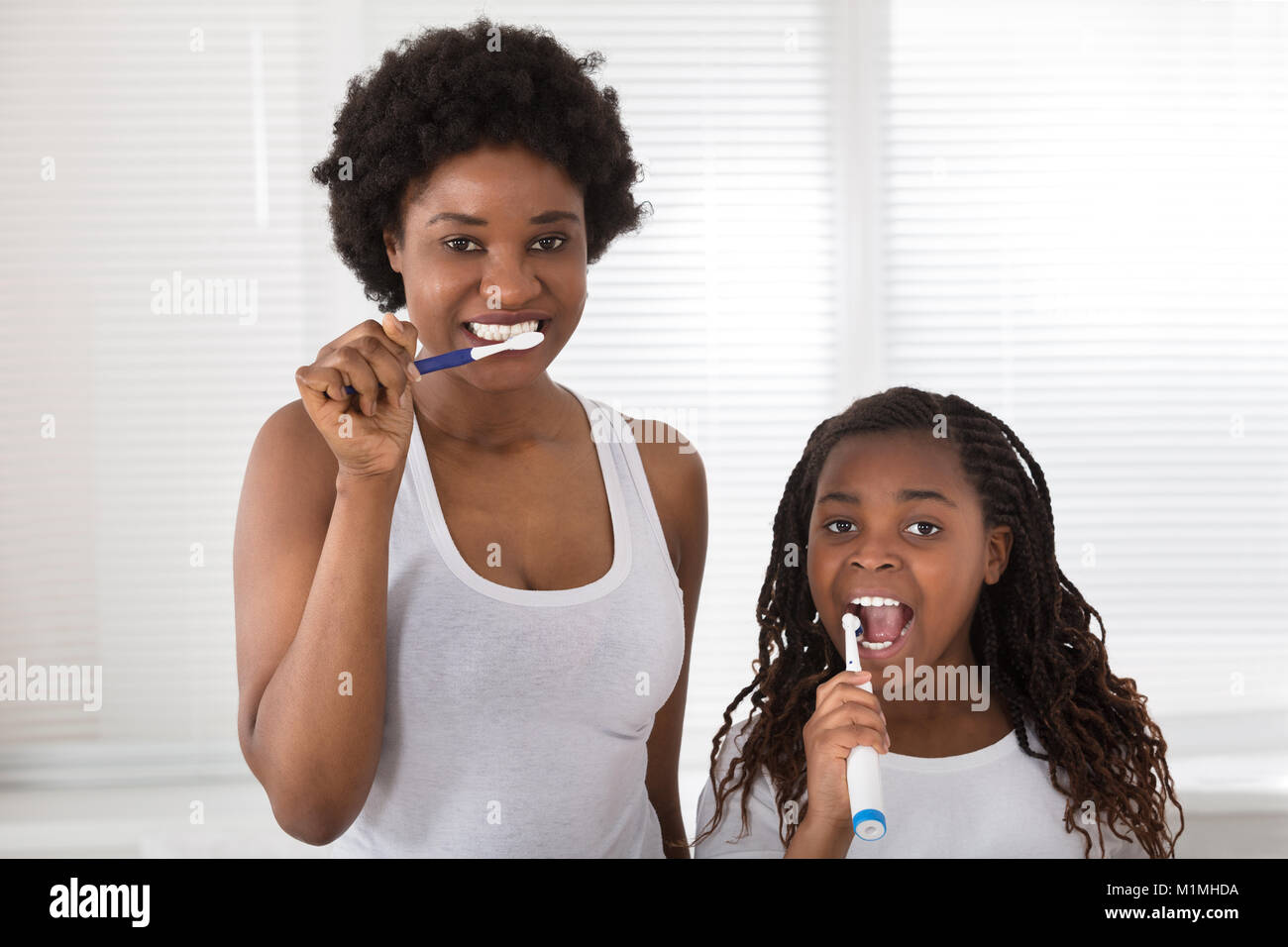 Afrikanische Mutter und Tochter ihre Zähne putzen Im Badezimmer Stockfoto