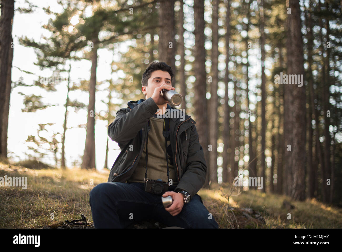 Mann im Wald Trinkwasser sitzen Stockfoto