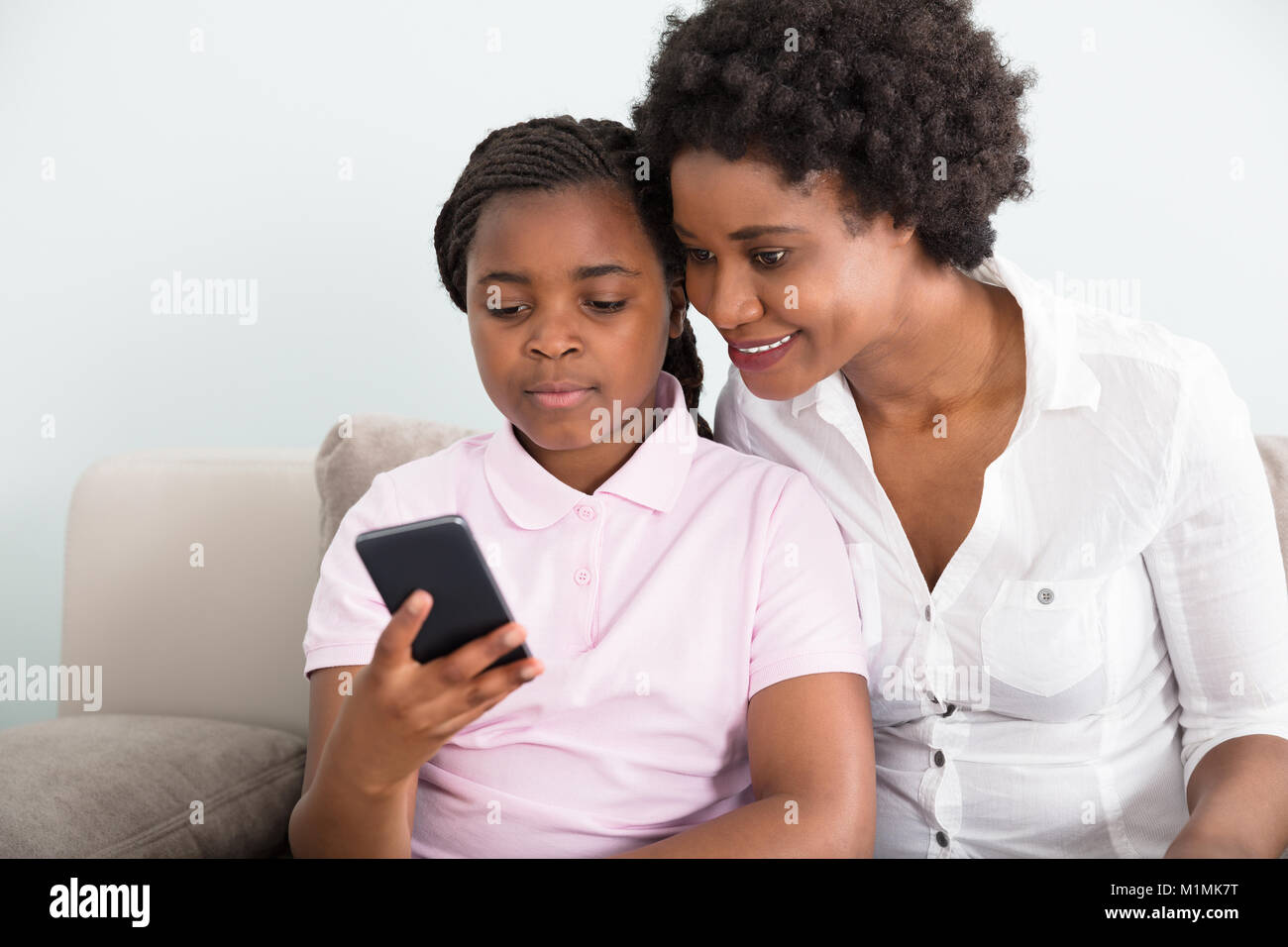 Mutter und Tochter sitzen auf der Couch bei Smart Phone Suchen Stockfoto