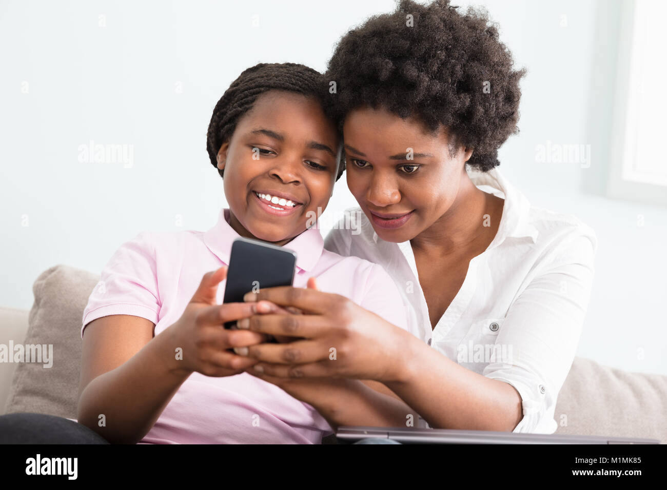 Mutter und Tochter sitzen auf der Couch bei Smart Phone Suchen Stockfoto