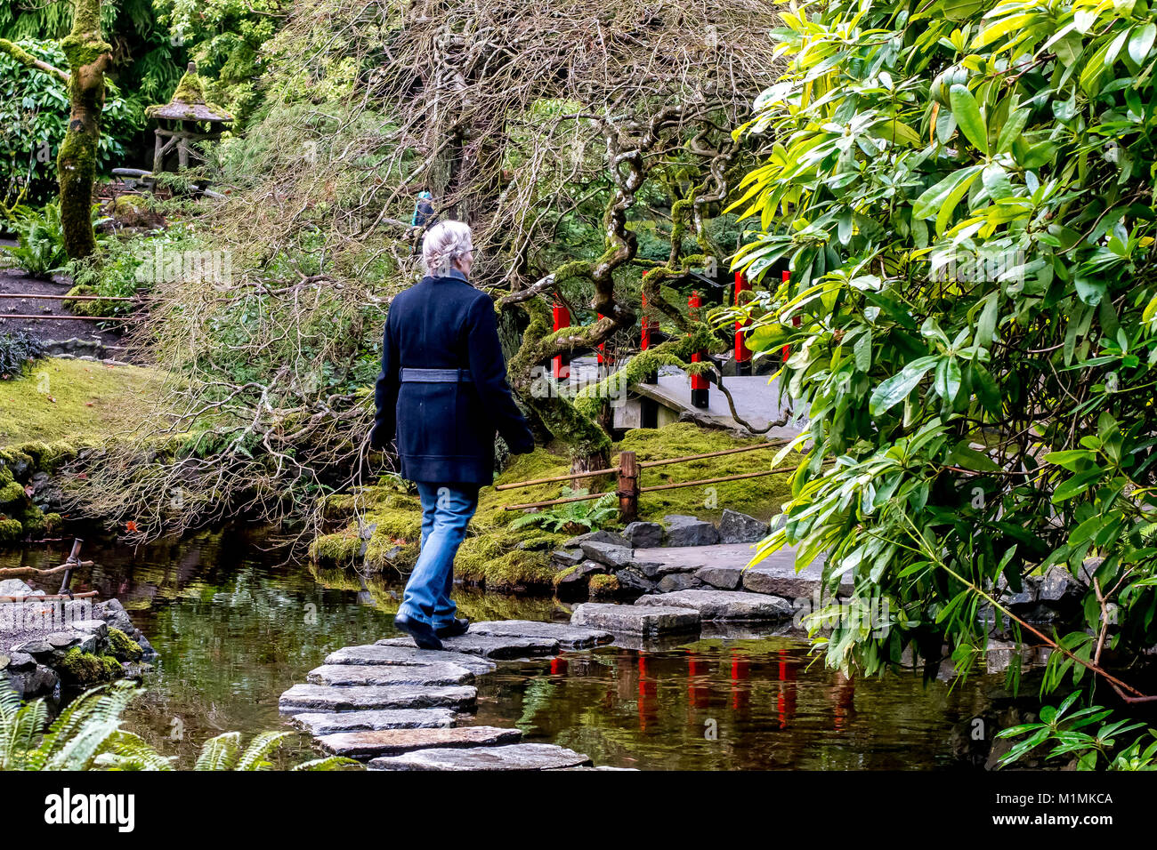 Frau gehen über Trittsteine, die in einem Teich Stockfoto