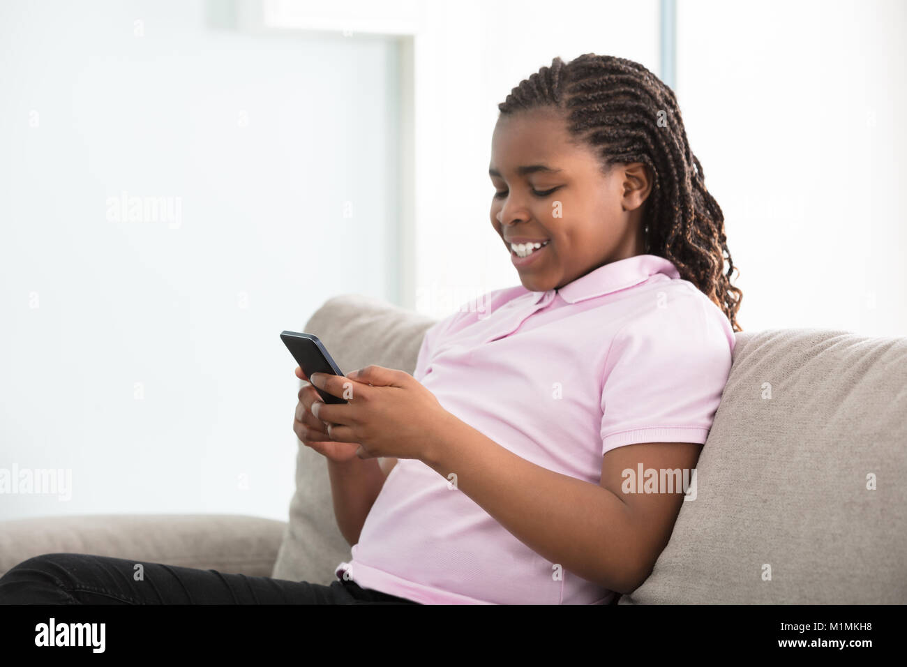 Close-up ein afrikanisches Mädchen sitzen auf der Couch mit Smart Phone Stockfoto