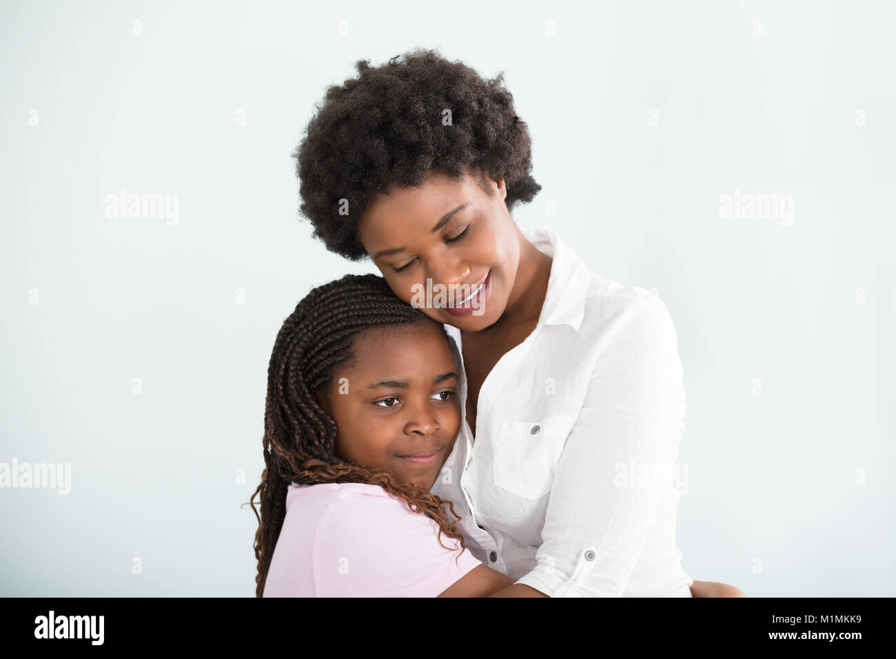 Lächelnd afrikanische Mutter und Tochter umarmt Gemeinsam gegen den weißen Hintergrund Stockfoto