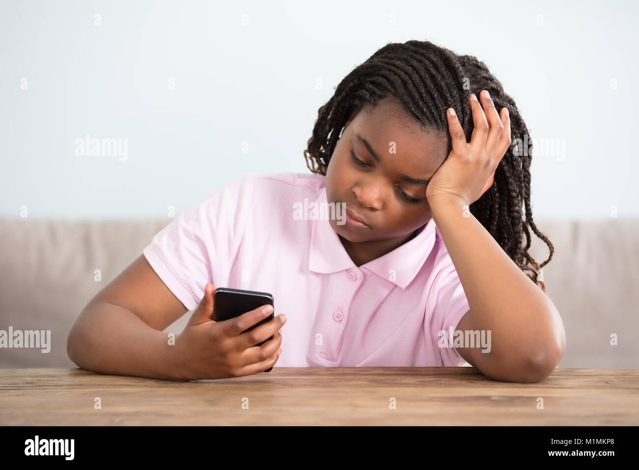 Nahaufnahme einer Afrikanischen gelangweilt Mädchen mit Handy Stockfoto