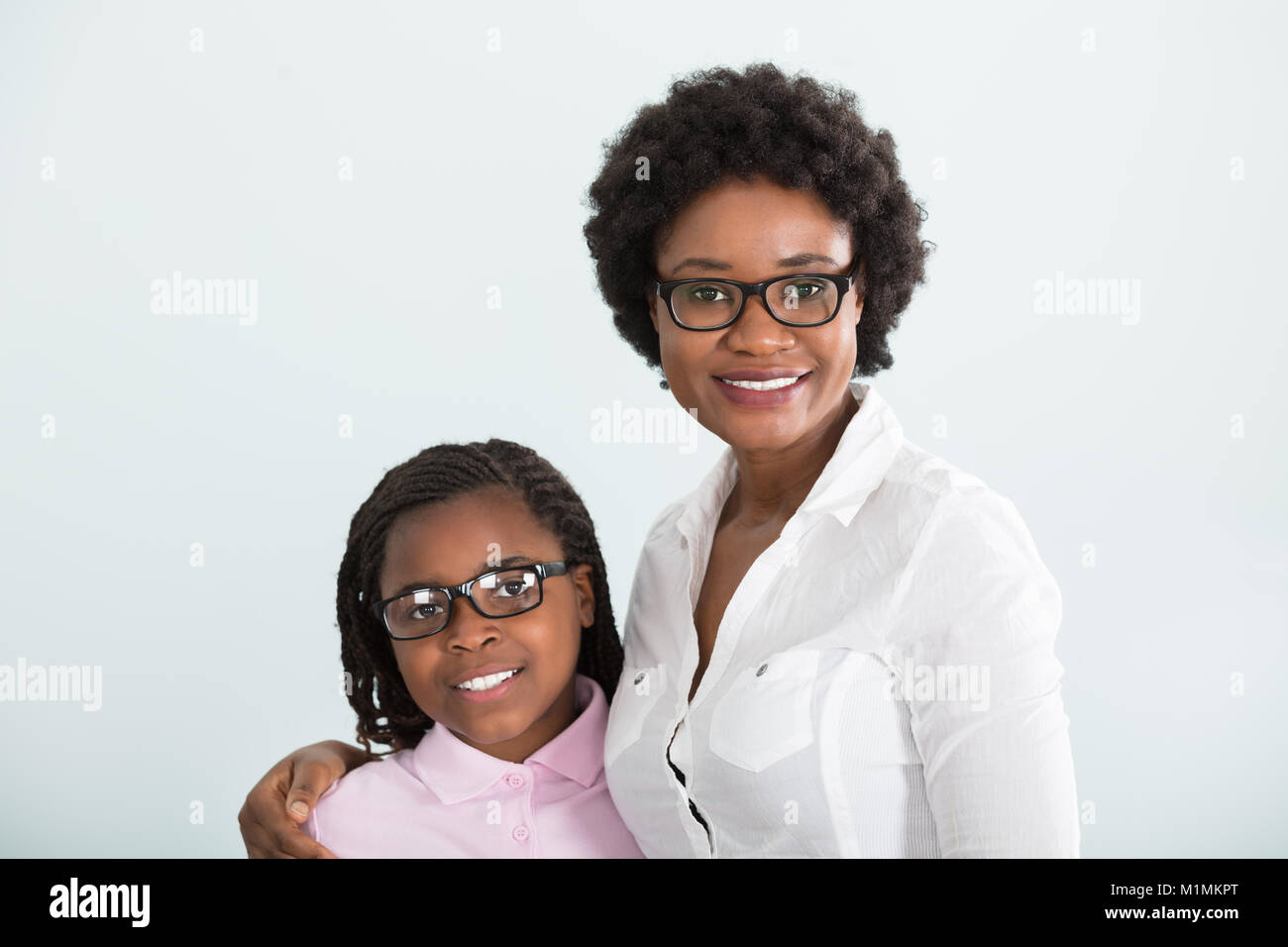 Porträt eines lächelnden Tochter und Mutter mit Brille vor weißem Hintergrund Stockfoto