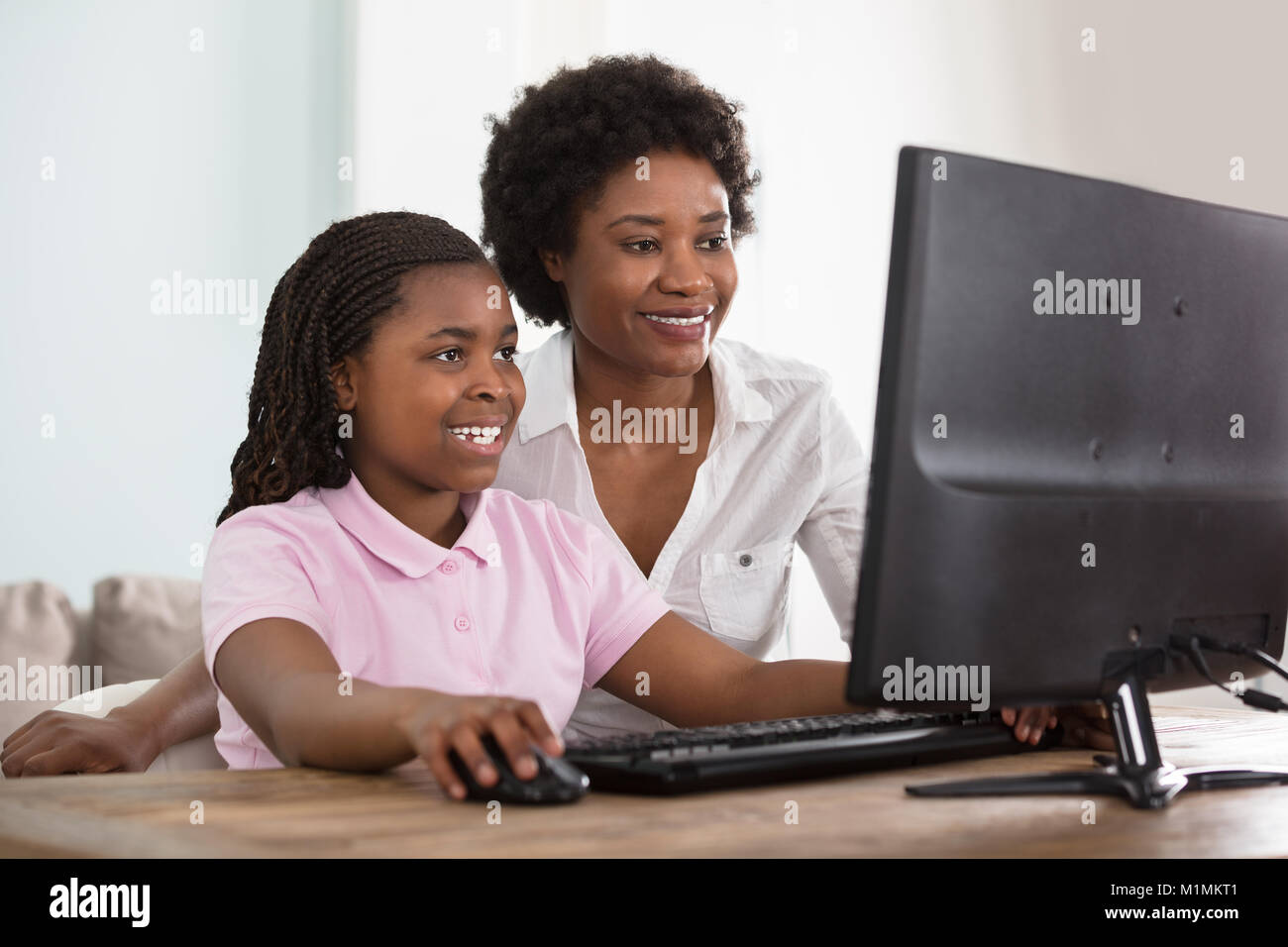 Eine afrikanische Mutter und Tochter am Computer auf dem Tisch zu Hause Suchen Stockfoto