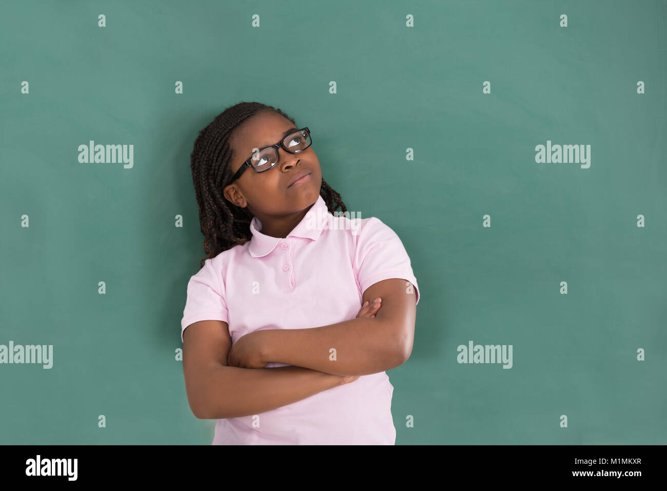 Close-up von Nachdenklich afrikanisches Mädchen Stehend gegen die grüne Tafel im Klassenzimmer Stockfoto