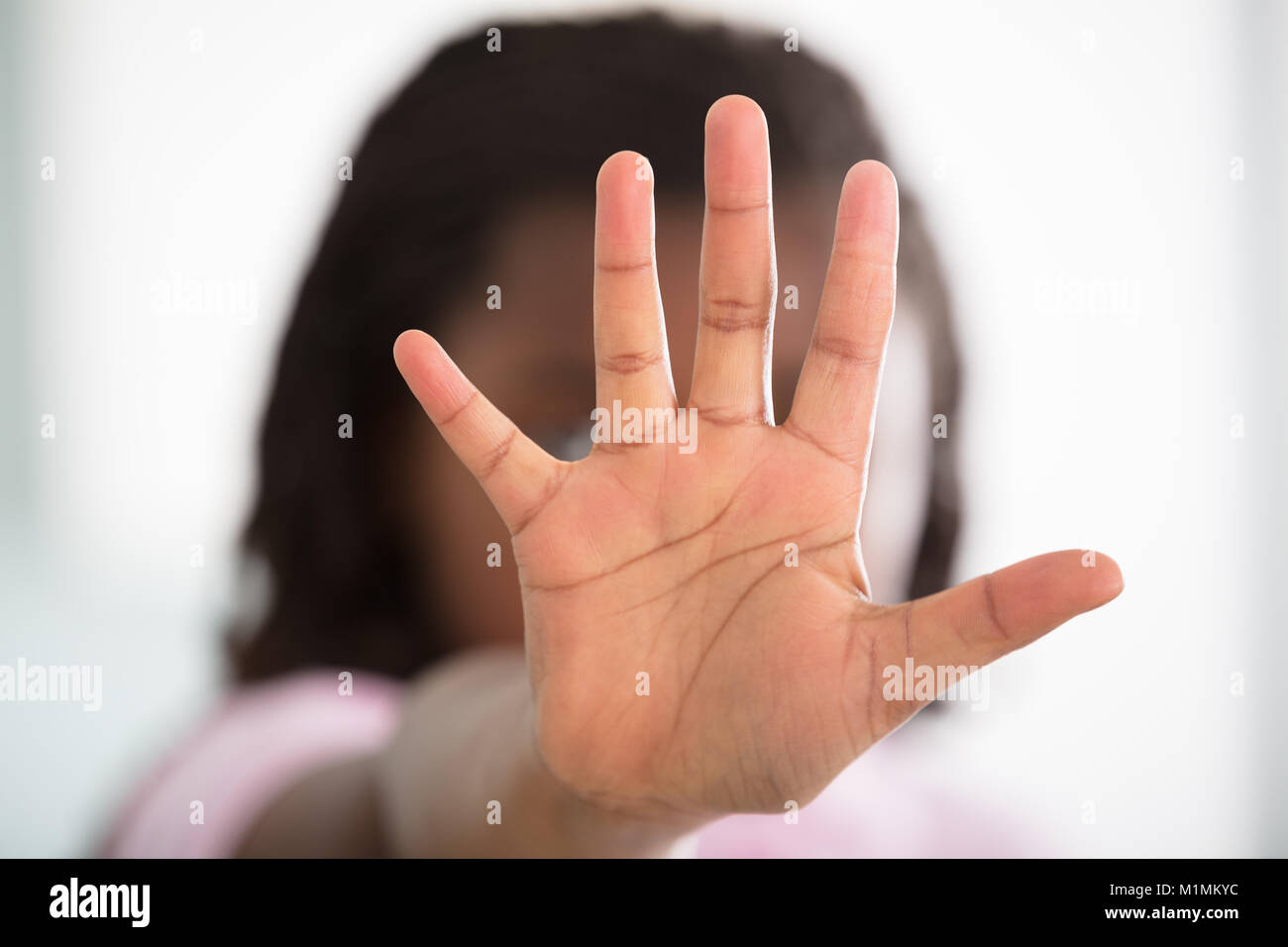 Mädchen machen Stop-Schild auf defokussiertem Hintergrund Stockfoto