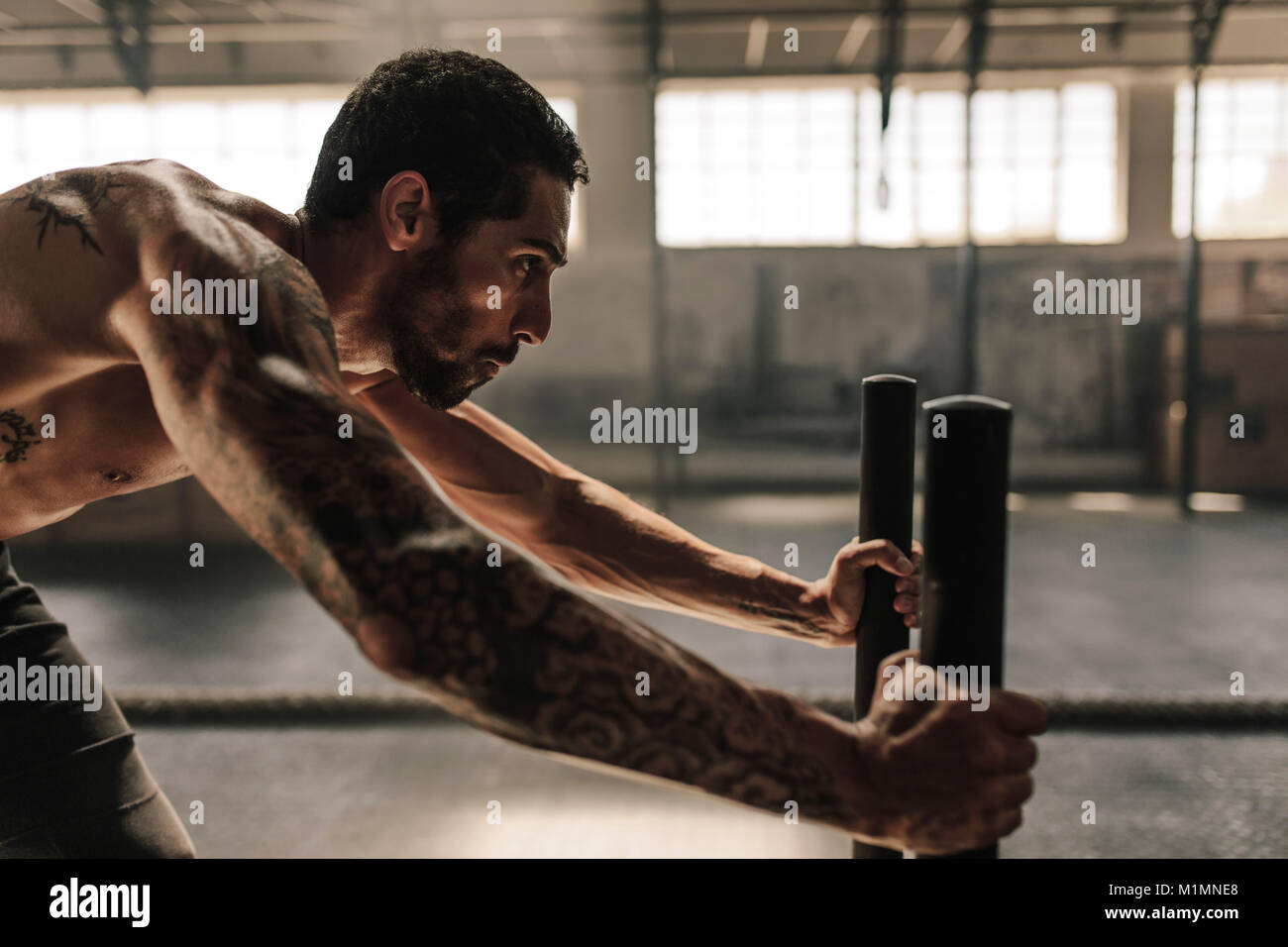 Seitenansicht des starken Mannes Schlitten drücken an der Turnhalle. Athleten, die leistungsstarke Übung bei Cross Training Gym. Stockfoto