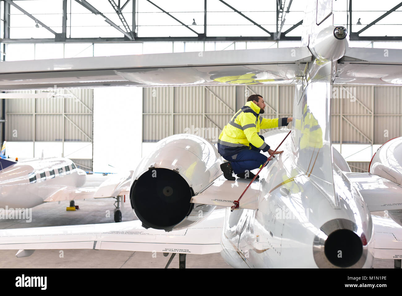 Bodenpersonal des Flughafens prüft die Technik und Sicherheit eines Jets im Hangar Stockfoto