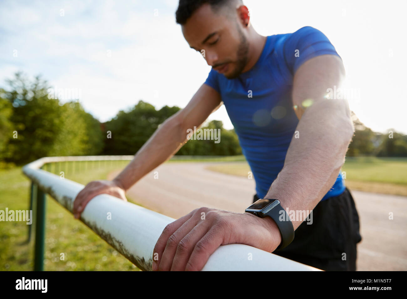 Männliche Athlet schiefen auf Zaun an der Laufstrecke, Nahaufnahme Stockfoto