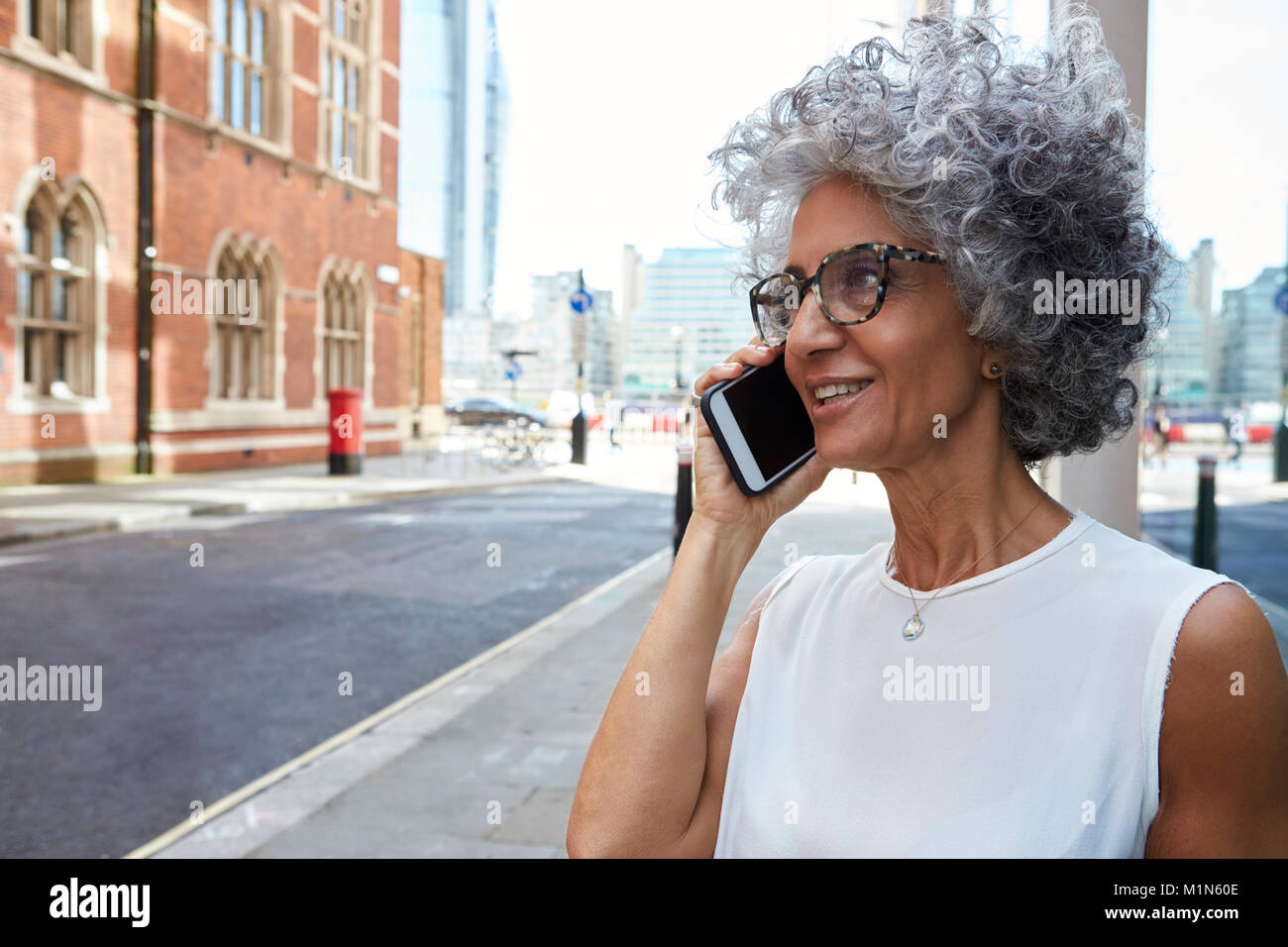 Frau mittleren Alters am Telefon sprechen in der Straße der Stadt, in der Nähe Stockfoto