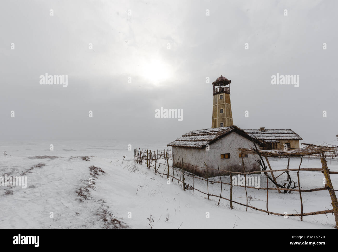 Alten hölzernen Leuchtturm am Rand des gefrorenen Hafen mit bewölktem Himmel Stockfoto