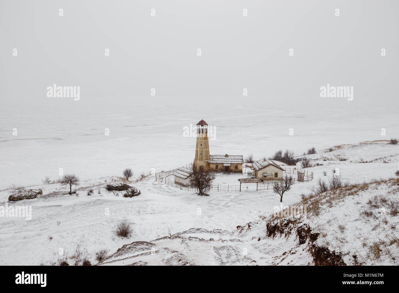 Alten hölzernen Leuchtturm am Rand des gefrorenen Hafen mit bewölktem Himmel Stockfoto