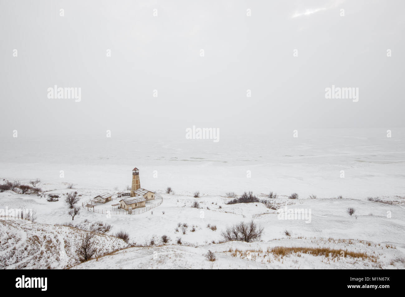 Alten hölzernen Leuchtturm am Rand des gefrorenen Hafen mit bewölktem Himmel Stockfoto