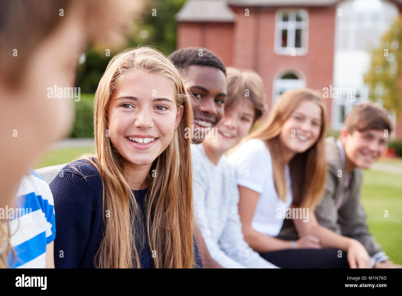 Gruppe von Jugendlichen Schüler sitzen außerhalb der Schule Gebäude Stockfoto