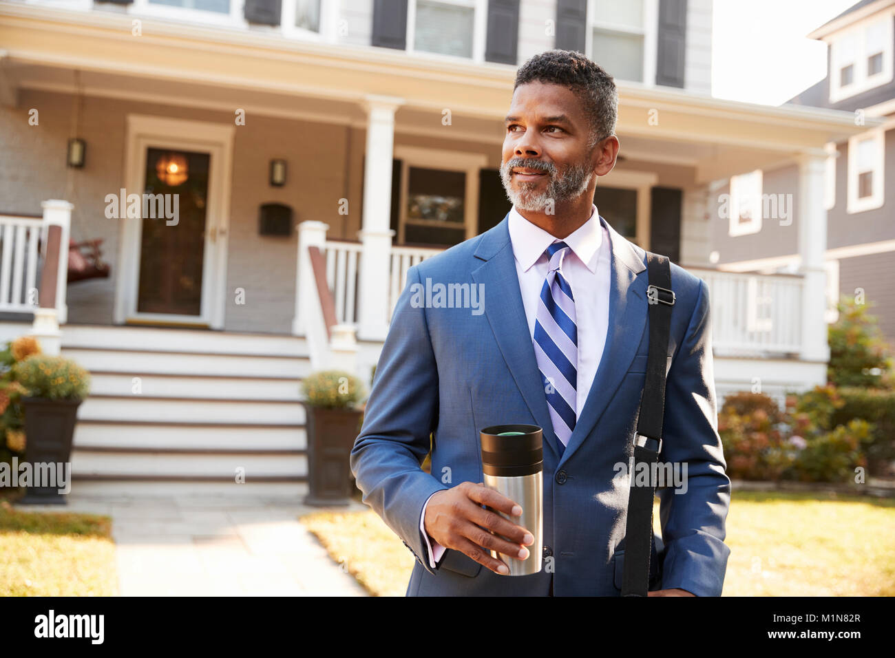 Geschäftsmann mit Tasse Kaffee verlassen Suburban House für die Arbeit Stockfoto