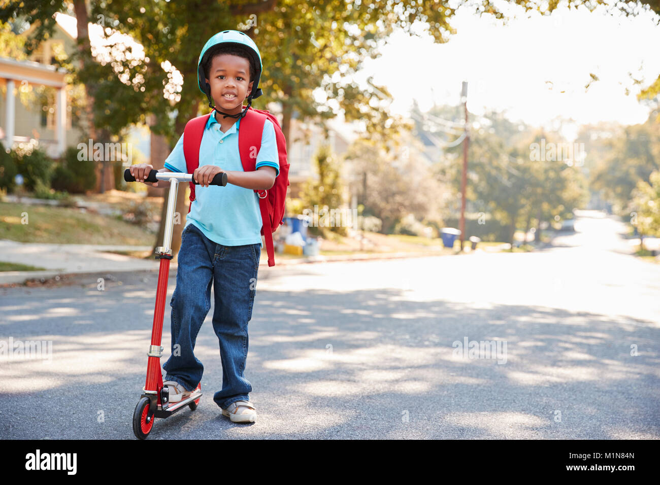 Junge Reiten Roller entlang der Straße zur Schule Stockfoto