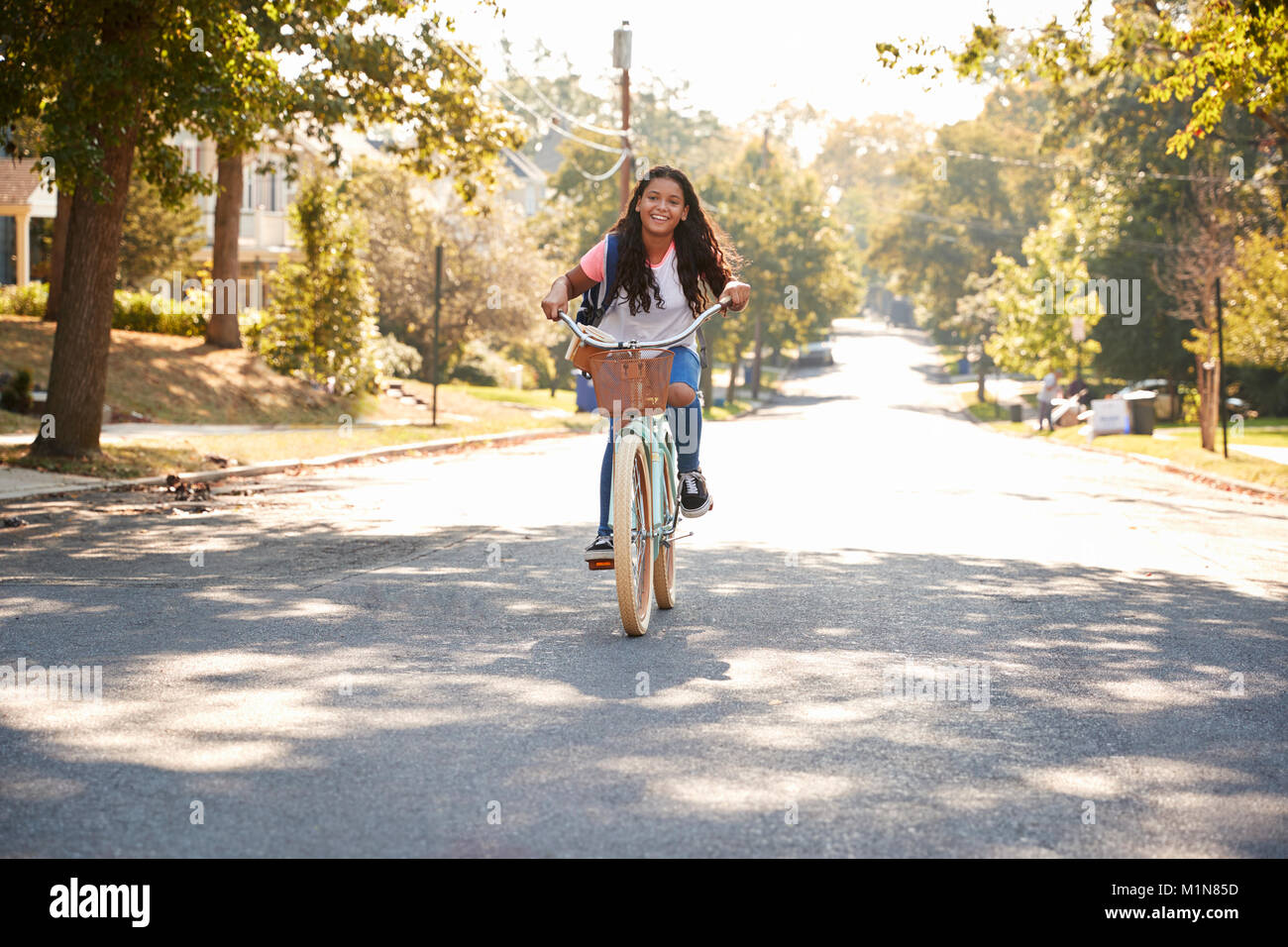Mädchen Reiten Fahrrad entlang der Straße zur Schule Stockfoto