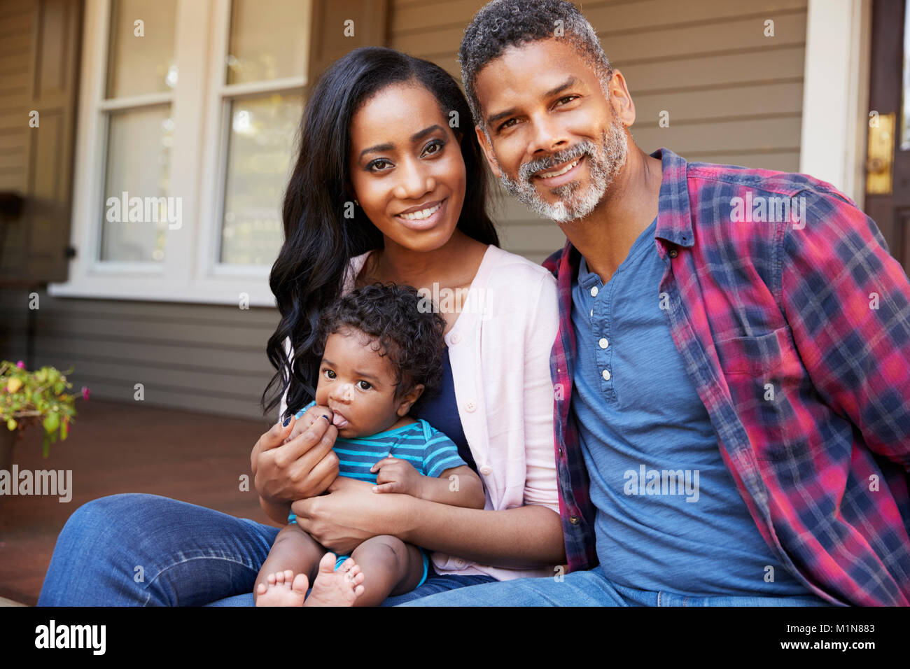 Familie mit Baby Sohn sitzen auf Schritte, die Bis zur Halle Home Stockfoto
