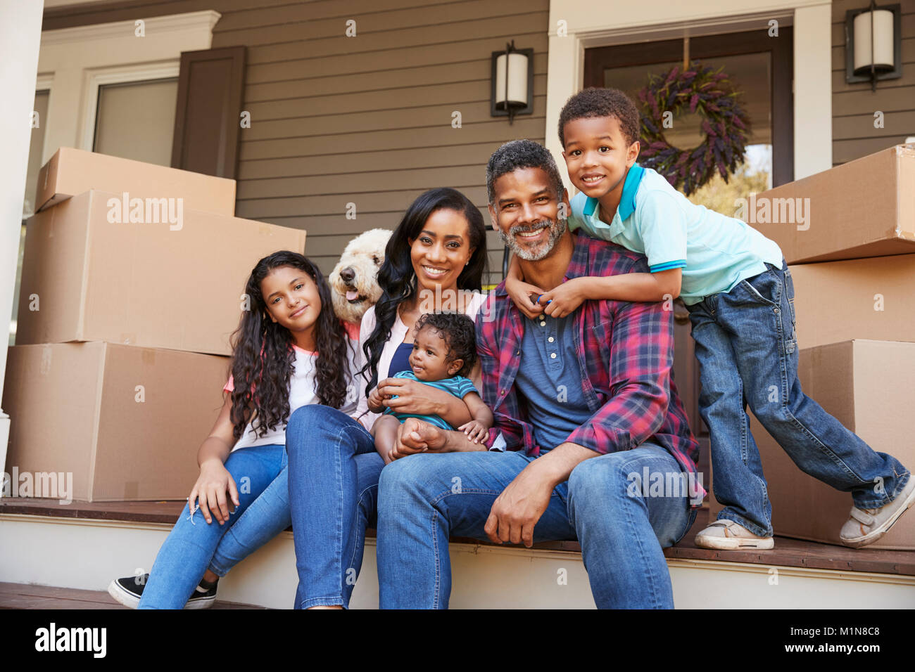 Familie mit Kindern und Hund ausserhalb des Hauses am Umzugstag Stockfoto