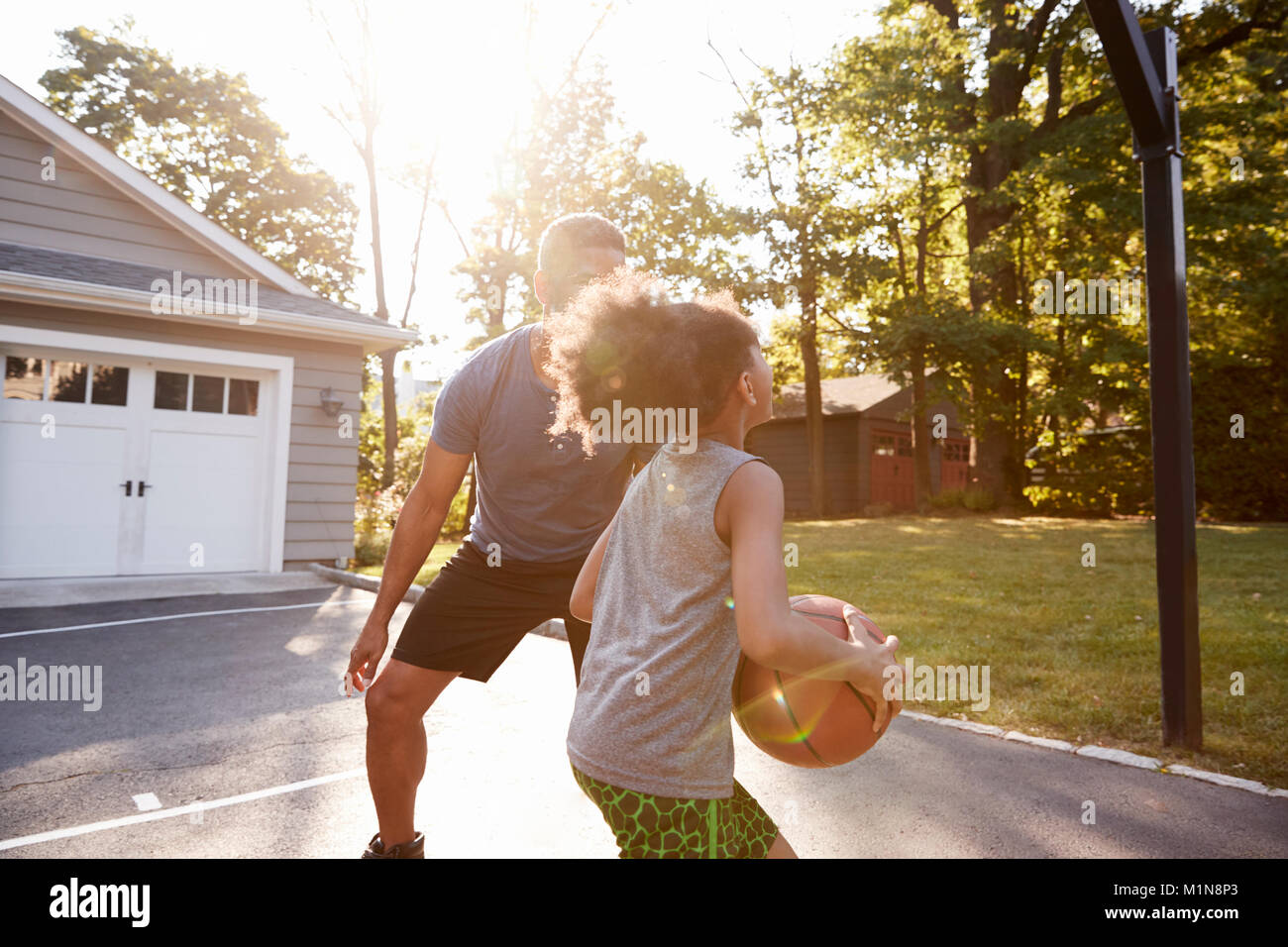Vater und Sohn Basketball spielen in der Einfahrt zu Hause Stockfoto