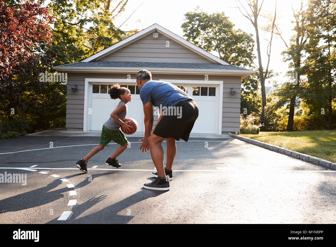 Vater und Sohn Basketball spielen in der Einfahrt zu Hause Stockfoto
