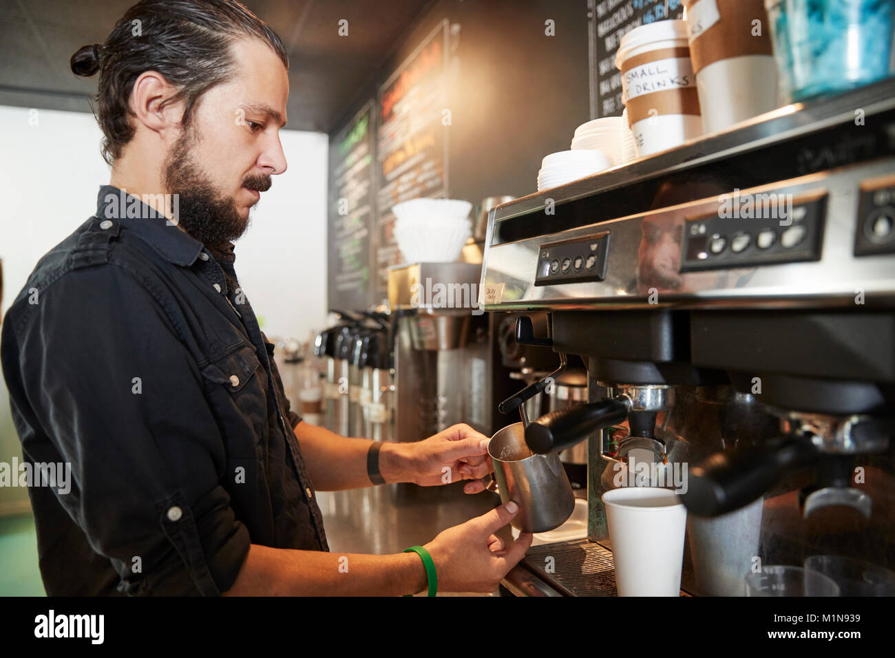 Männliche Barista mit Kaffeemaschine hinter der Theke im Cafe Stockfoto