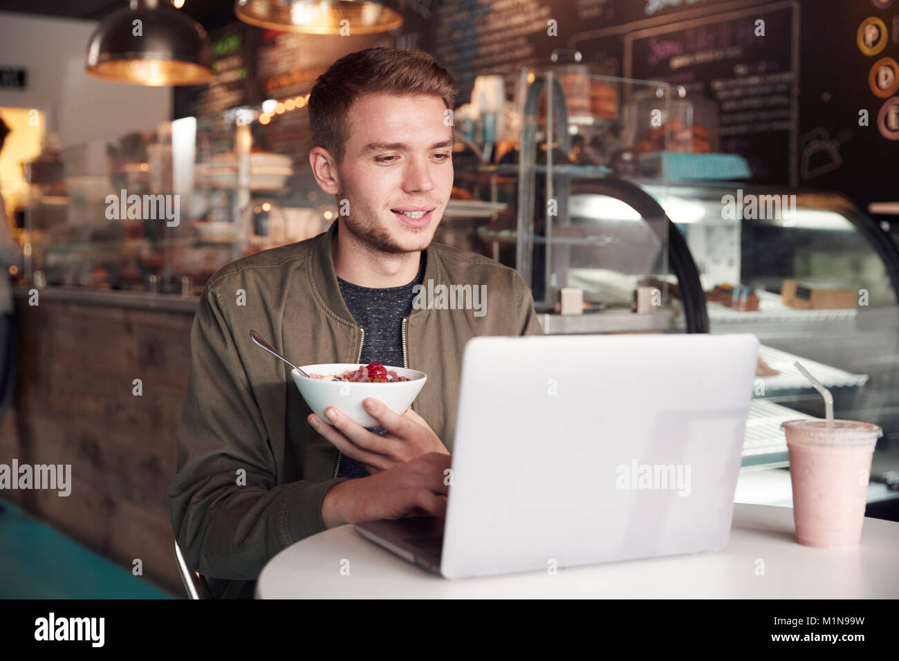 Junger Mann mit Laptop im Cafe essen Frühstück Stockfoto