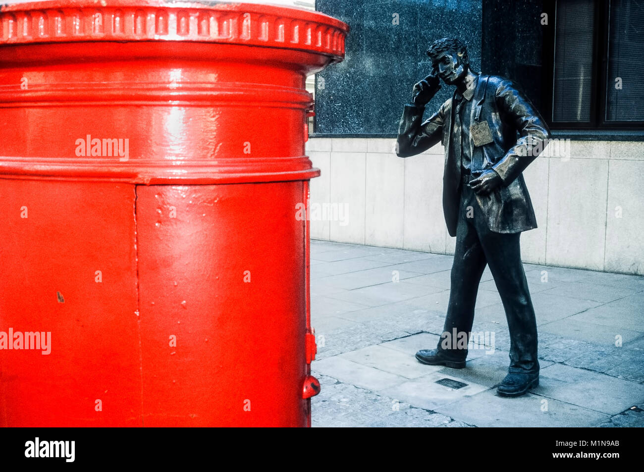 Stadt London Statue einer Liffe Händler mit Handy und im Vordergrund ein typisch roten Briefkasten. Stockfoto