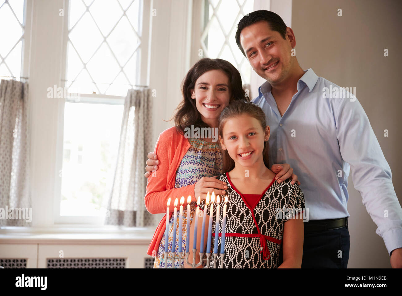 Jüdische Eltern und Tochter lächelnd, angezündete Kerzen auf menorah Stockfoto