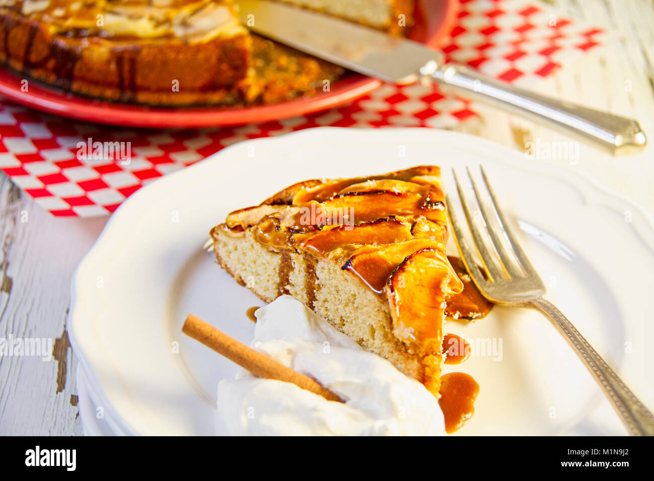 Eine Scheibe des salzigen Caramel Apfelkuchen garniert mit Zimt und Sahne ein beträufelt mit Karamellsauce Stockfoto