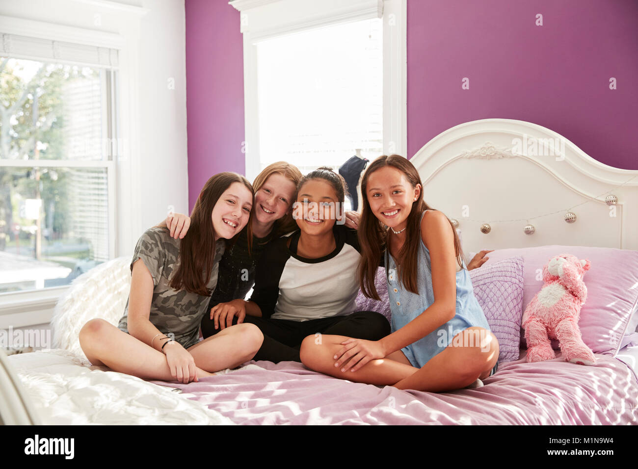 Vier jugendlich Mädchen sitzen auf dem Bett zusammen an der Kamera auf der Suche Stockfoto