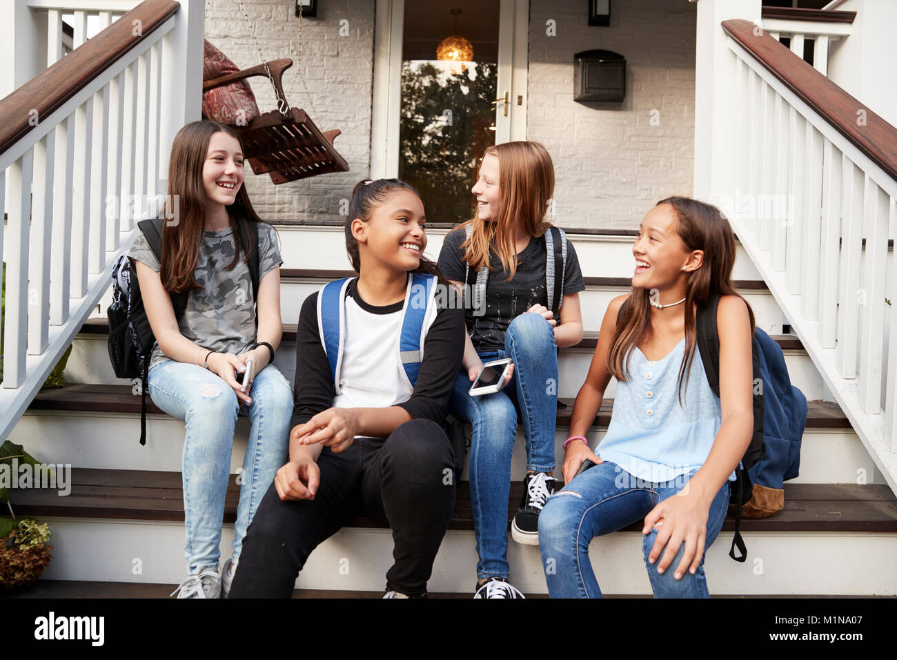 Junge Teen Girls auf der Vorderseite des Hauses mit Schultaschen Stockfoto