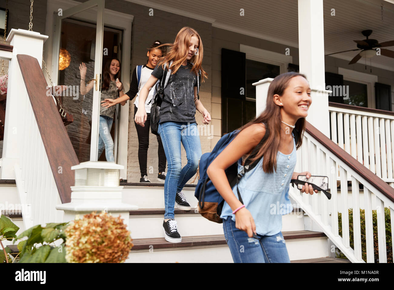 Vier jugendlich Mädchen verlassen Haus mit Schultaschen Stockfoto