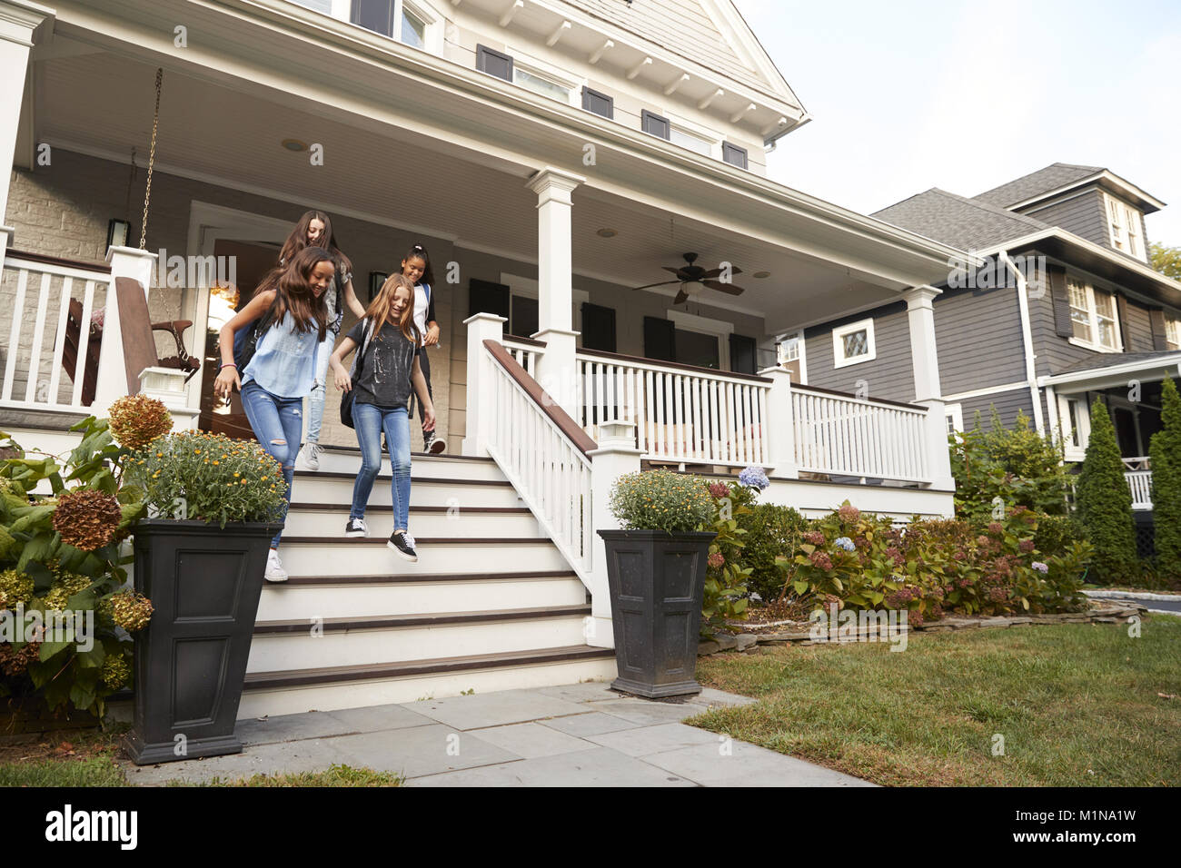 Vier jugendlich Freundinnen gehen hinunter Stufen vor dem Haus Stockfoto