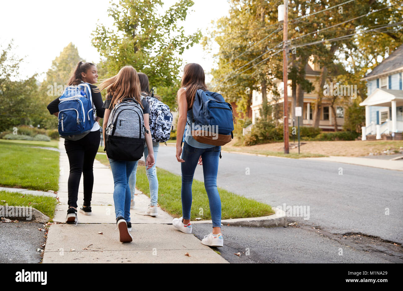 Vier junge jugendlich Mädchen zu Fuß zur Schule zusammen, Rückansicht Stockfoto