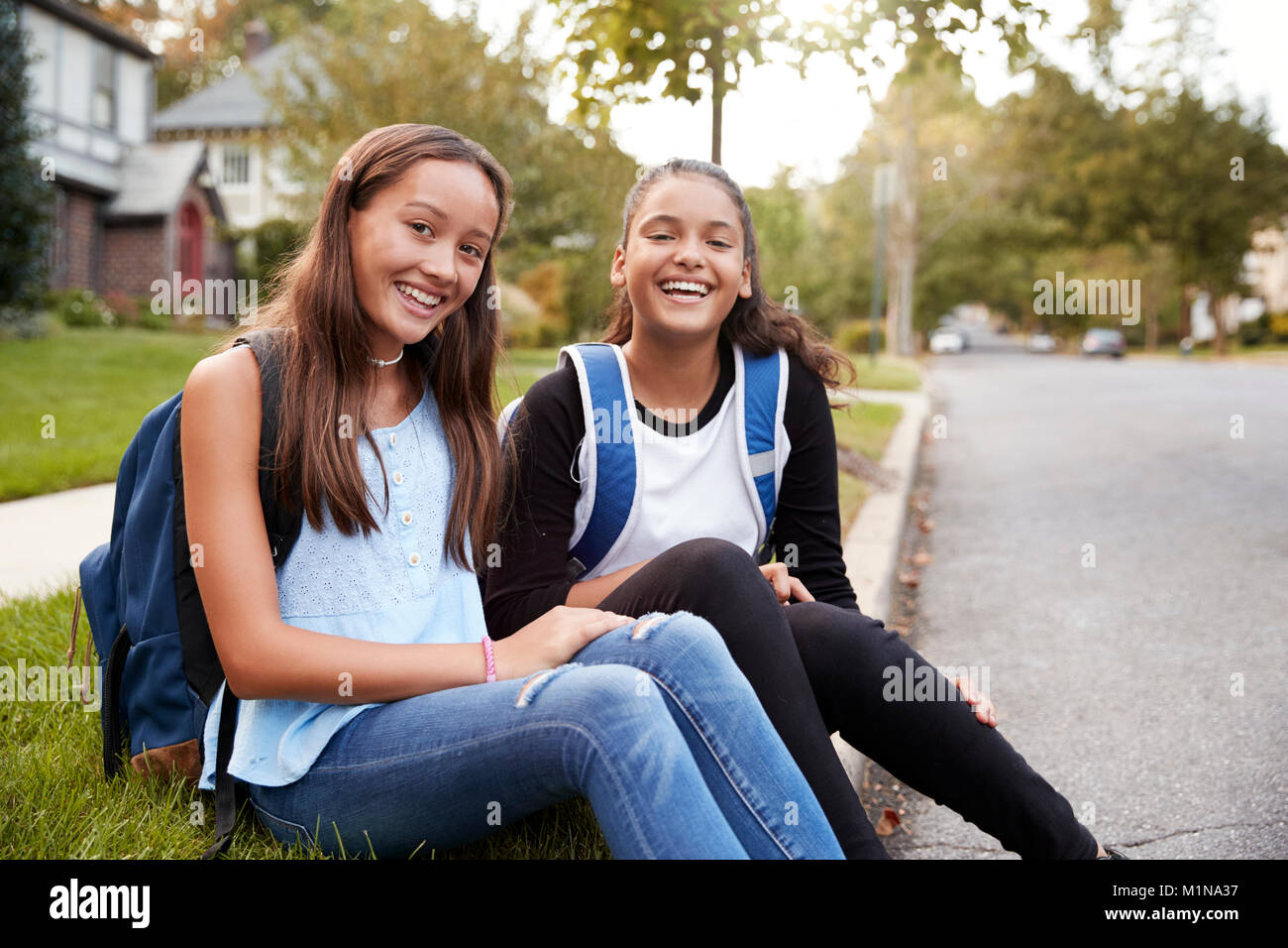Zwei jugendlich Freundinnen sitzen an den Straßenrand zu Kamera suchen Stockfoto