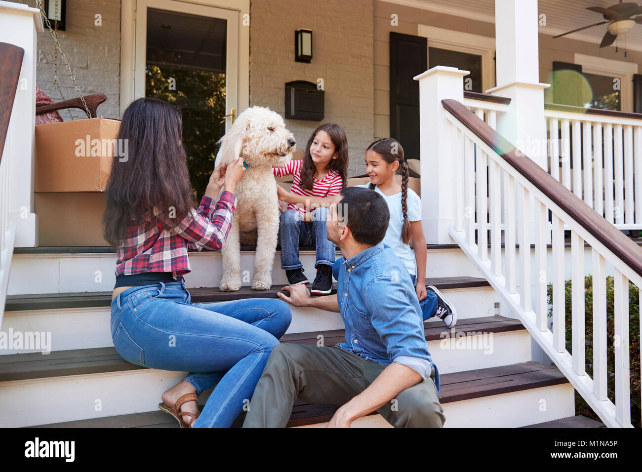 Familie mit Hund sitzen auf die Schritte der neuen Heimat unter Umzug in Tag Stockfoto