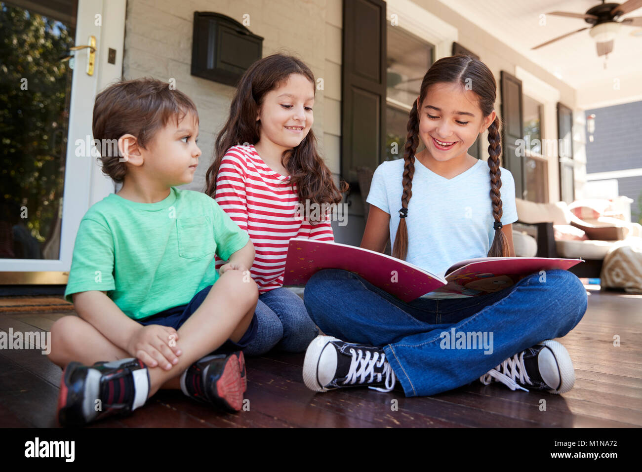 Gruppe der Kinder sitzen auf der Veranda des Hauses gemeinsam Bücher lesen Stockfoto