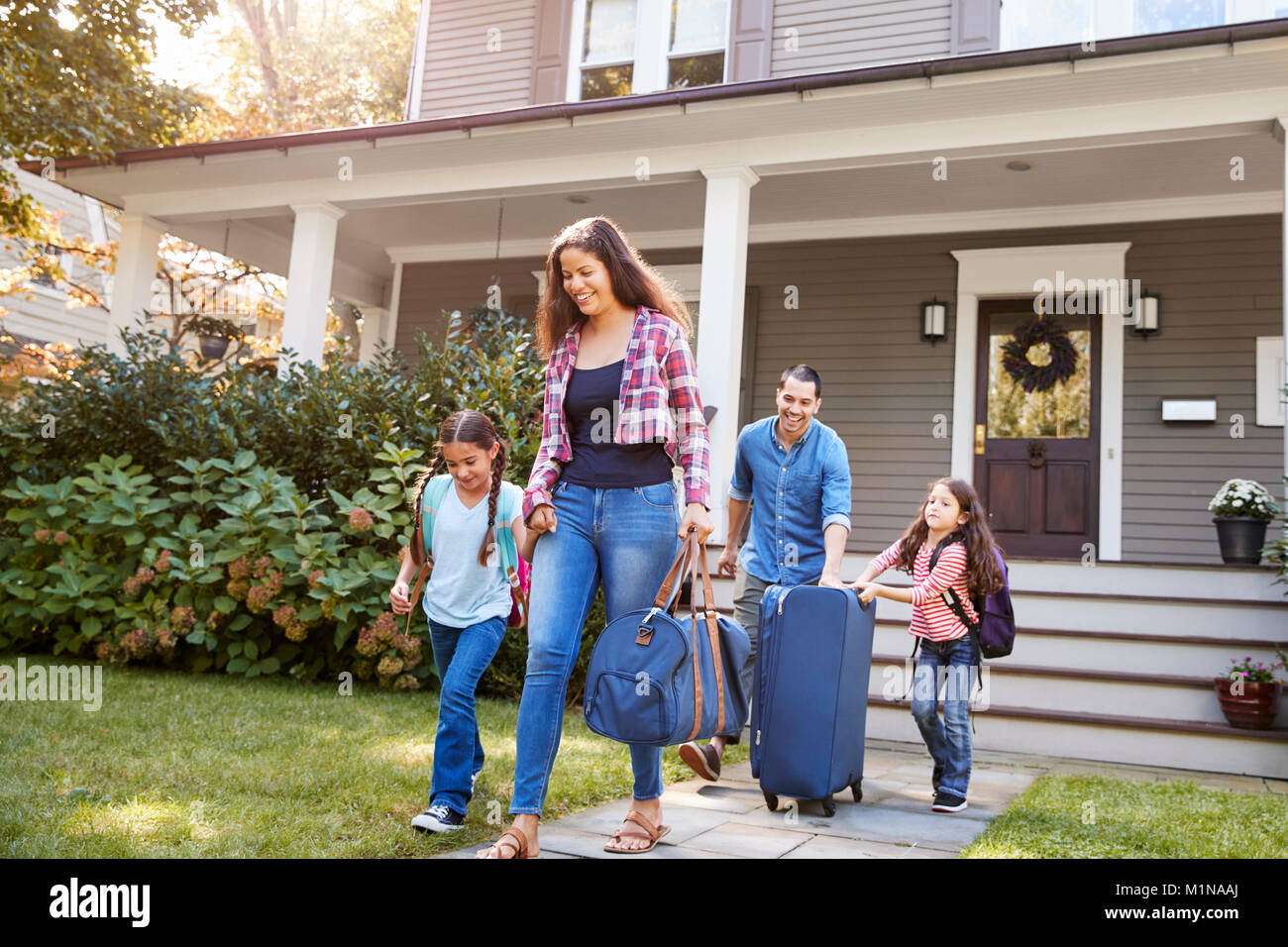 Familie mit Gepäck verlassen Haus für Ferienhäuser Stockfoto