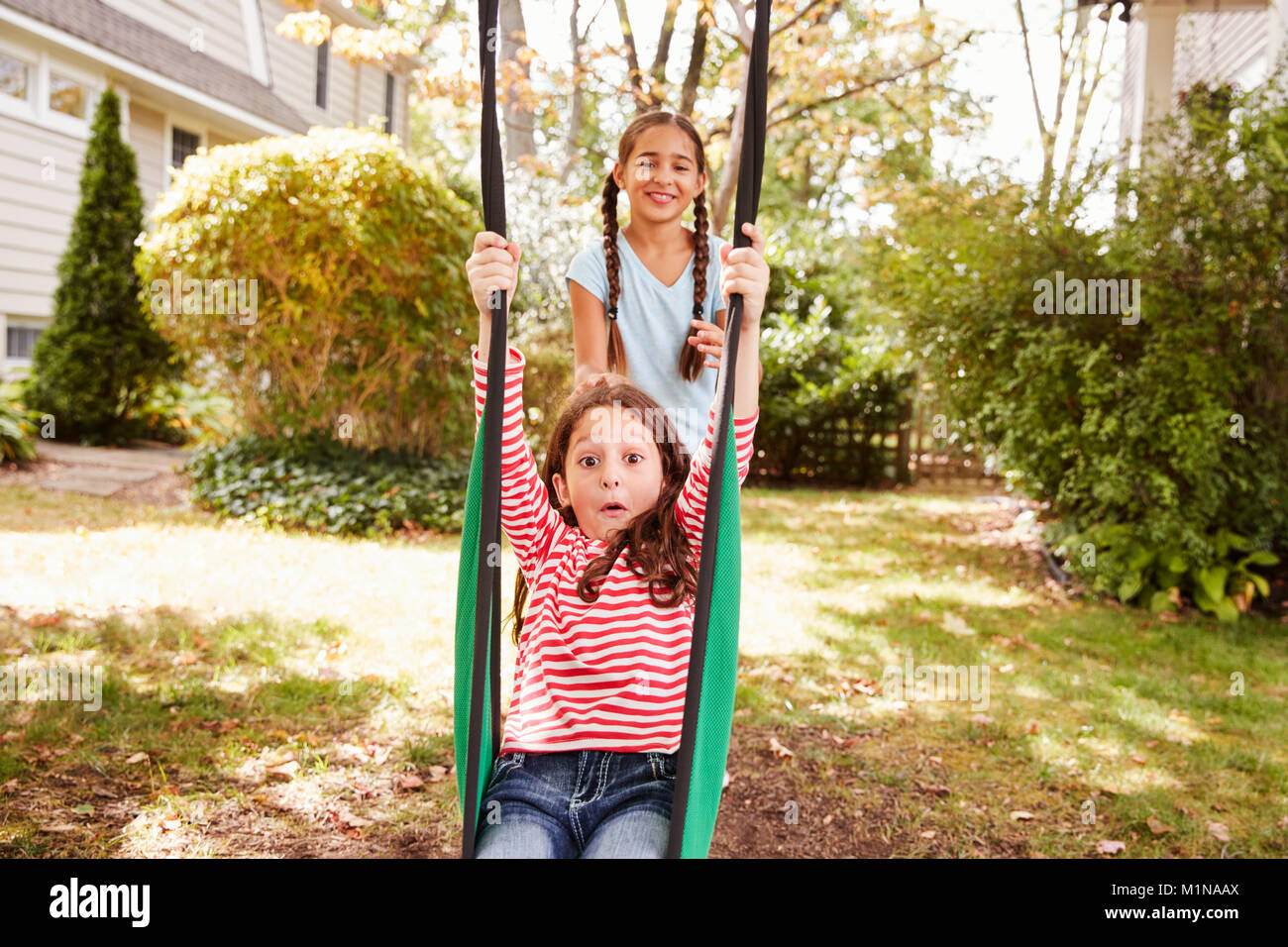 Zwei Schwestern Spaß auf Garten Schaukel zu Hause Stockfoto