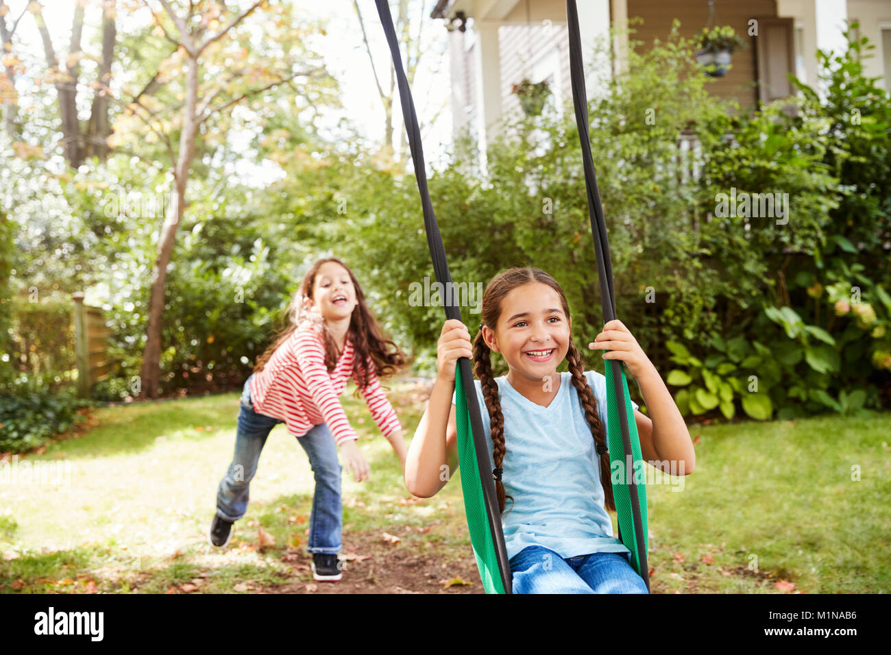 Zwei Schwestern Spaß auf Garten Schaukel zu Hause Stockfoto