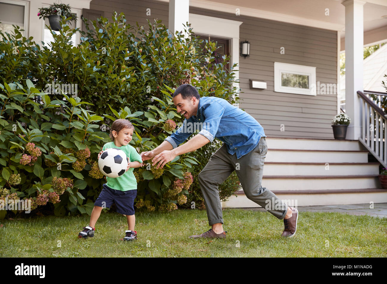 Vater Fußball spielen im Garten mit Sohn Stockfoto