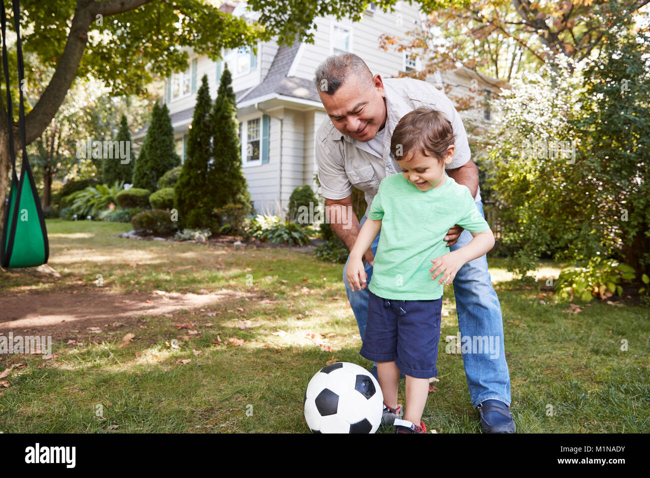 Großvater Fußball spielen im Garten mit Enkel Stockfoto