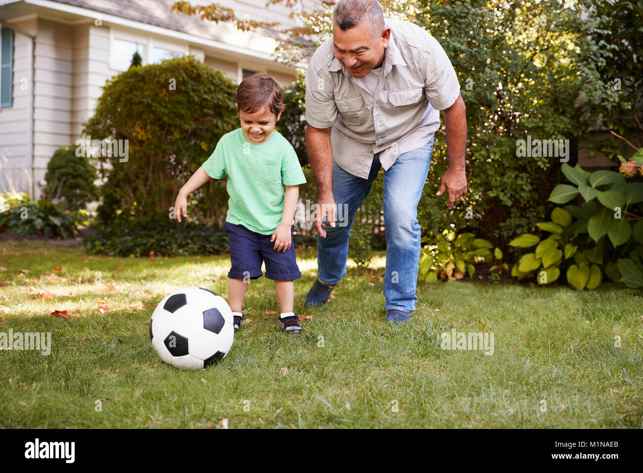 Großvater Fußball spielen im Garten mit Enkel Stockfoto