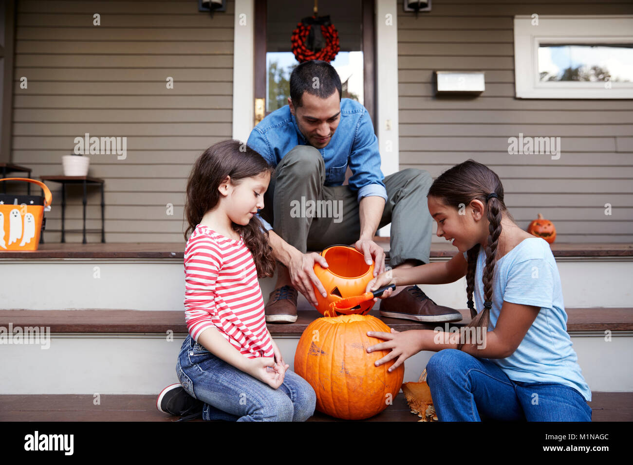 Vater und Tochter schnitzen Halloween Kürbis auf Haus Schritte Stockfoto