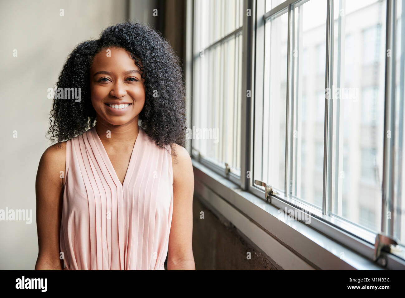 Junge schwarze Business woman von Fenster zu Kamera suchen Stockfoto