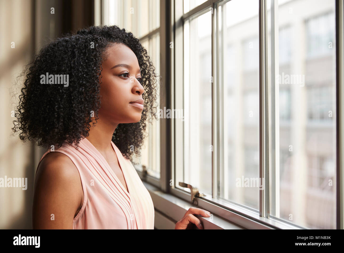Junge schwarze Geschäftsfrau Blick aus Fenster Stockfoto